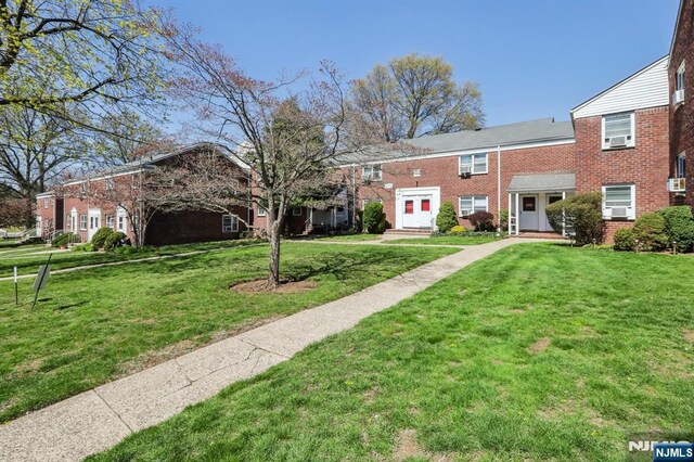 multi unit property with brick siding and a front yard
