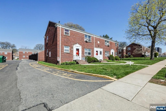 view of front of house with brick siding, a front lawn, and a residential view