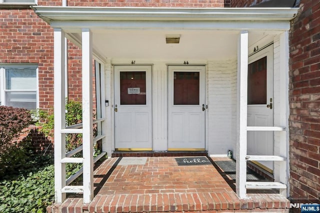 entrance to property with covered porch and brick siding