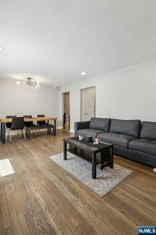 living area with recessed lighting, wood finished floors, and a notable chandelier