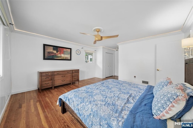 bedroom featuring crown molding, baseboards, visible vents, and wood finished floors