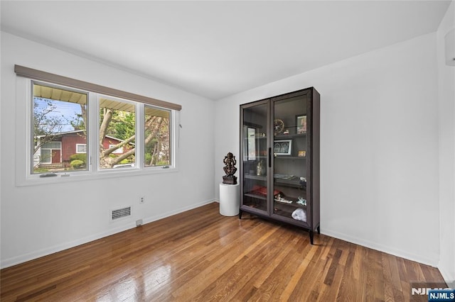 empty room featuring baseboards, visible vents, and wood finished floors