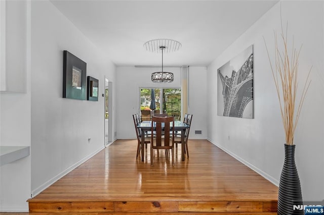 dining space with baseboards, a chandelier, visible vents, and light wood-style floors