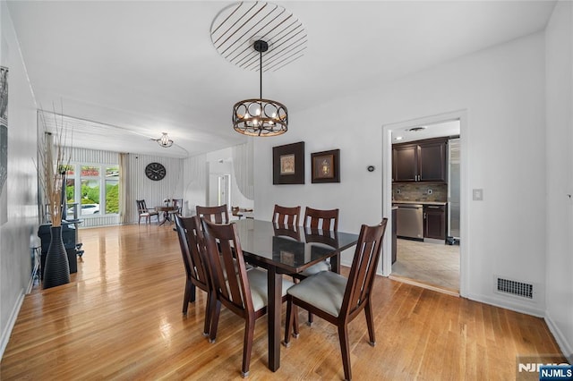 dining space with baseboards, visible vents, an inviting chandelier, and light wood finished floors