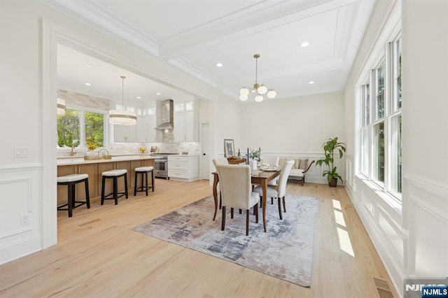 dining area with visible vents, wainscoting, ornamental molding, and light wood-style floors