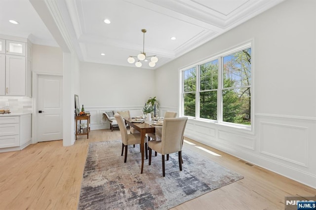 dining space featuring visible vents, ornamental molding, a decorative wall, and light wood-type flooring