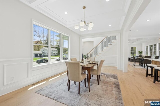dining area with stairway, light wood-style floors, a decorative wall, and a healthy amount of sunlight