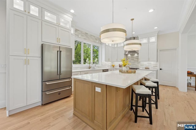 kitchen with a center island, tasteful backsplash, light countertops, light wood finished floors, and high end fridge