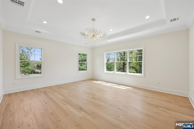 unfurnished room with a tray ceiling, visible vents, and plenty of natural light