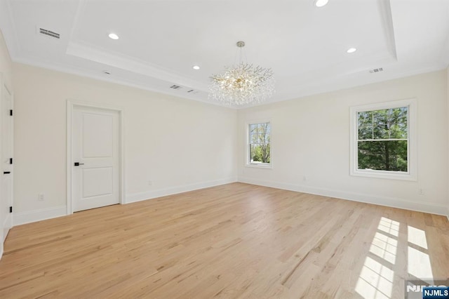 spare room featuring visible vents, light wood-type flooring, a raised ceiling, a notable chandelier, and recessed lighting