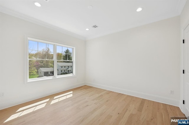 spare room with crown molding, baseboards, and light wood-style flooring