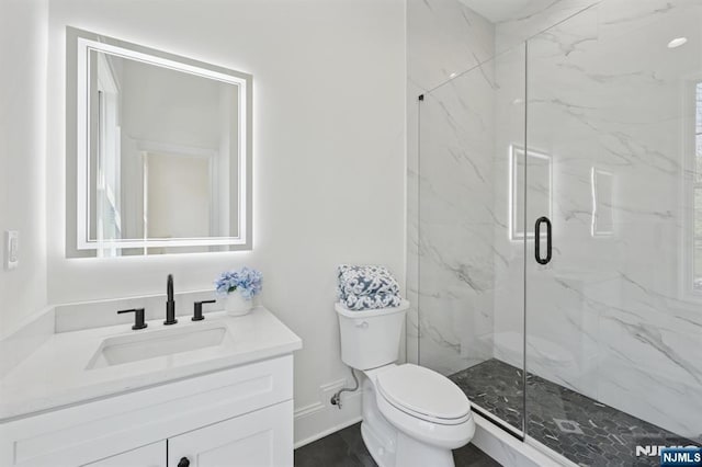 bathroom with toilet, baseboards, a marble finish shower, and vanity