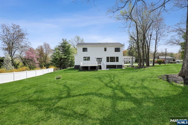 rear view of property with a lawn, fence, and a deck