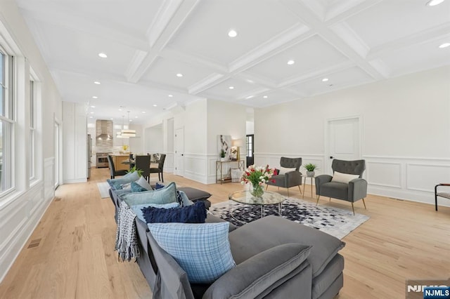 living area featuring a decorative wall, beamed ceiling, and coffered ceiling