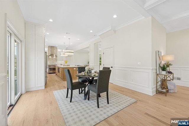 dining room featuring light wood-style floors, recessed lighting, a wainscoted wall, and ornamental molding