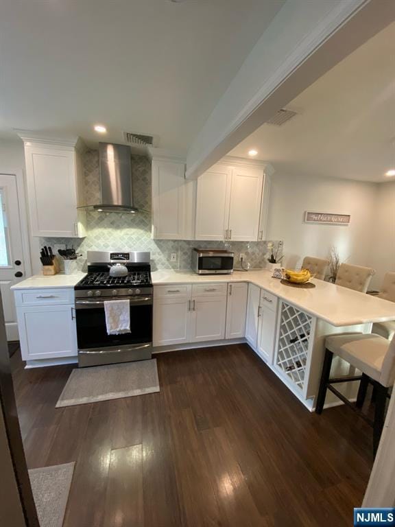 66 Lexington Ave, Rochelle Park, NJ 07662 - kitchen with white cabinetry, a peninsula, wall chimney exhaust hood, light countertops, and appliances with stainless steel finishes