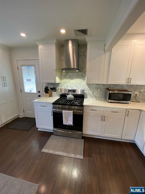 66 Lexington Ave, Rochelle Park, NJ 07662 - kitchen with stainless steel appliances, visible vents, wall chimney exhaust hood, light countertops, and white cabinets