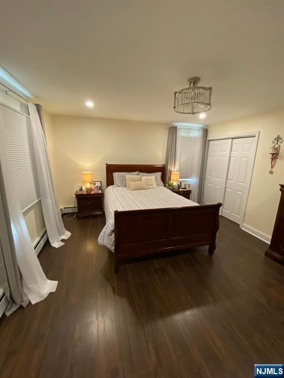 66 Lexington Ave, Rochelle Park, NJ 07662 - bedroom featuring a baseboard radiator, a closet, a baseboard heating unit, baseboards, and wood finished floors