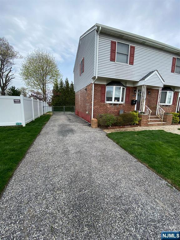 66 Lexington Ave, Rochelle Park, NJ 07662 - view of front of house featuring a front lawn, brick siding, driveway, and fence
