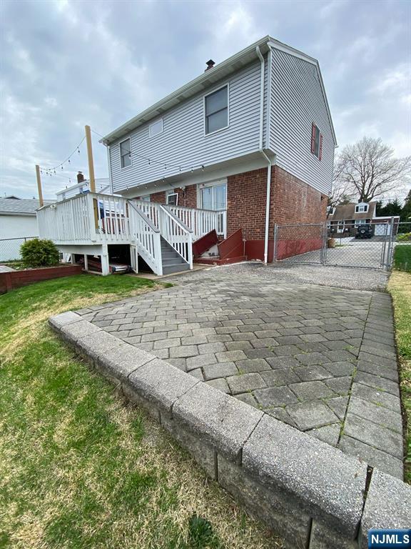 66 Lexington Ave, Rochelle Park, NJ 07662 - back of property featuring brick siding, a gate, fence, and a wooden deck