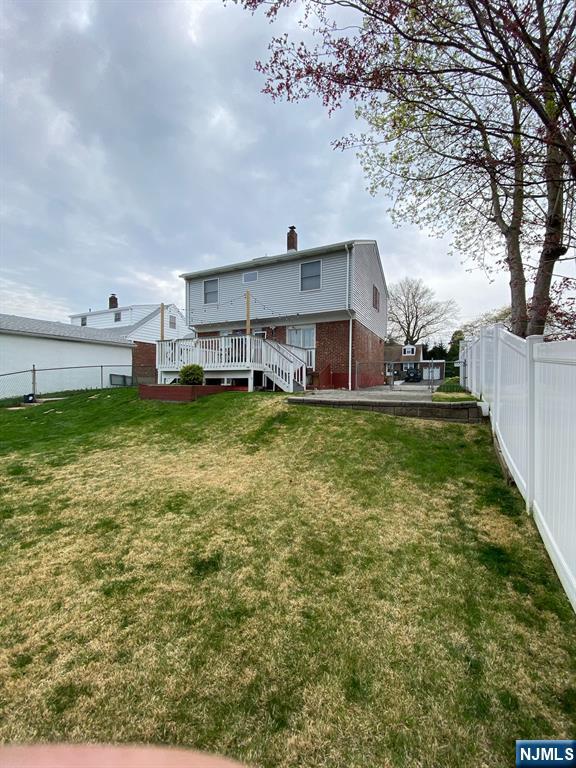 66 Lexington Ave, Rochelle Park, NJ 07662 - rear view of property featuring a lawn, a chimney, fence, and a wooden deck