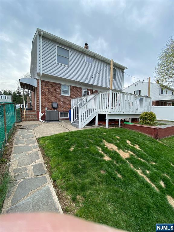 66 Lexington Ave, Rochelle Park, NJ 07662 - back of property with a yard, brick siding, fence, cooling unit, and a deck