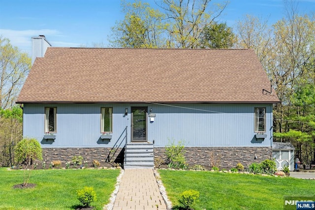 view of front facade with a chimney, roof with shingles, stone siding, and a front yard