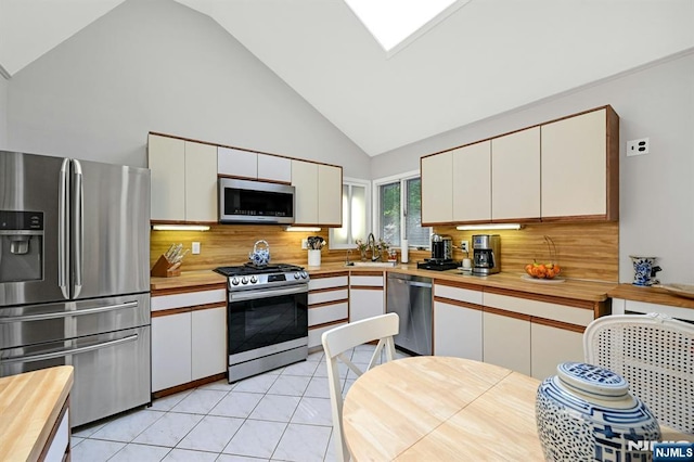 kitchen with backsplash, a sink, appliances with stainless steel finishes, and butcher block counters