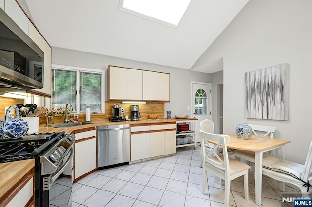 kitchen featuring butcher block countertops, white cabinets, a sink, backsplash, and stainless steel appliances