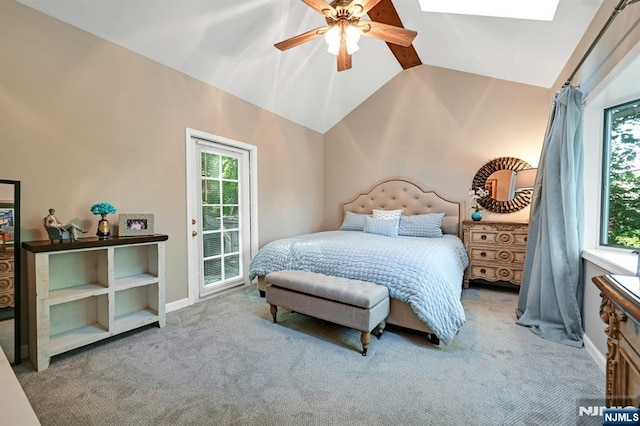 carpeted bedroom with baseboards, multiple windows, ceiling fan, and vaulted ceiling with skylight