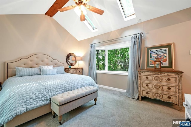 carpeted bedroom featuring a ceiling fan, baseboards, and vaulted ceiling with skylight