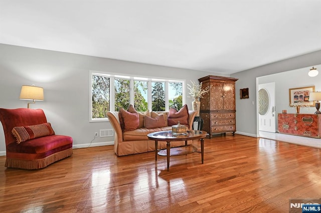 living area featuring baseboards, visible vents, and wood finished floors