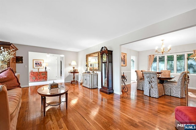 living area with baseboards, a notable chandelier, and wood finished floors