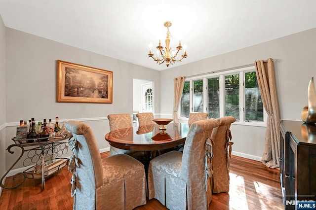 dining area featuring baseboards, wood finished floors, and a notable chandelier