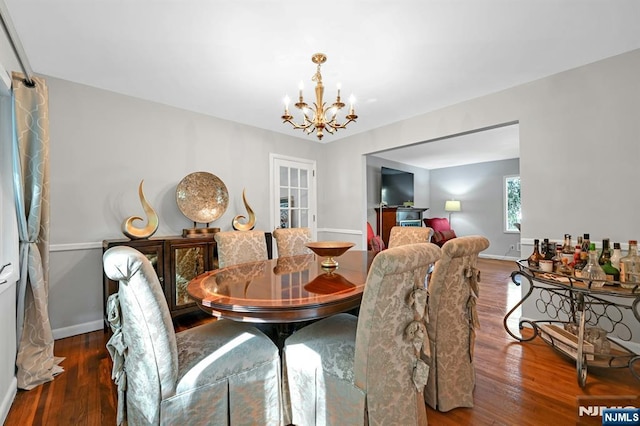 dining area featuring baseboards, a chandelier, and wood finished floors