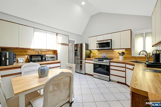 kitchen featuring decorative backsplash, a sink, high vaulted ceiling, stainless steel appliances, and white cabinetry