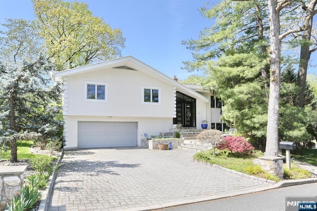 view of front of house featuring an attached garage, decorative driveway, and stucco siding