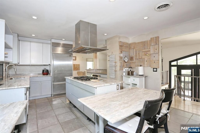 kitchen featuring open shelves, island range hood, a center island, a sink, and stainless steel appliances