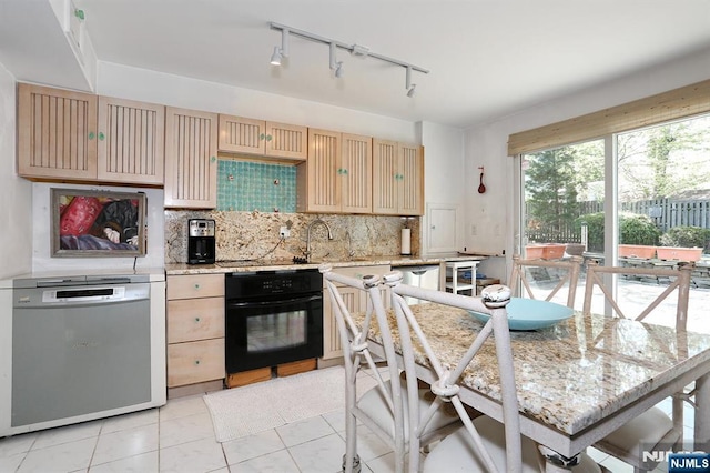 kitchen featuring a sink, dishwasher, black oven, rail lighting, and tasteful backsplash