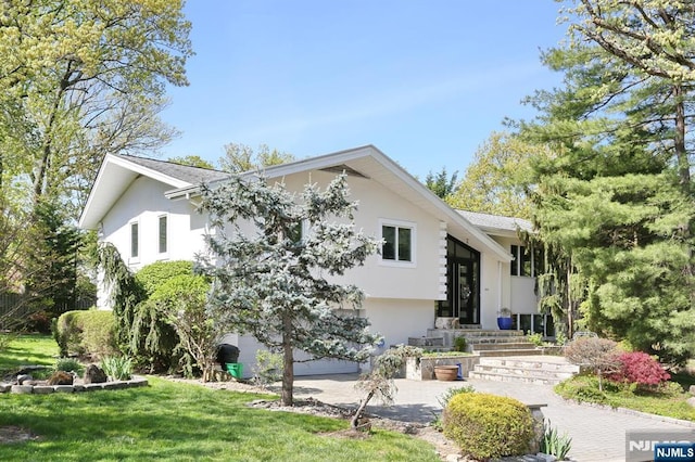 back of house featuring a yard and stucco siding