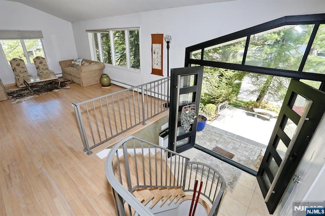 interior space with a healthy amount of sunlight, wood finished floors, lofted ceiling, and a baseboard radiator