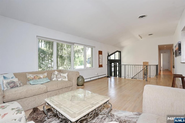 living room with wood finished floors, lofted ceiling, a baseboard heating unit, and visible vents