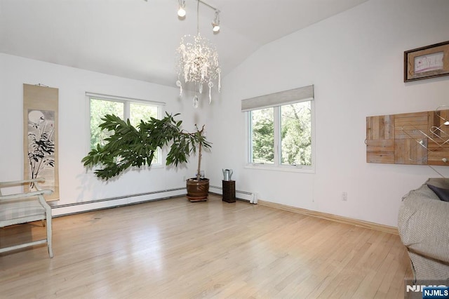 sitting room with a healthy amount of sunlight, a chandelier, wood finished floors, and lofted ceiling