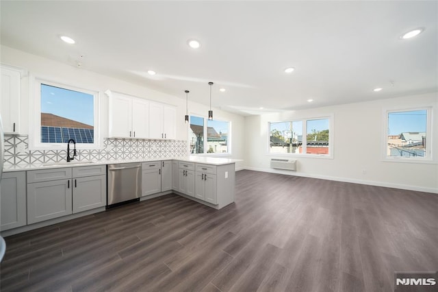 kitchen featuring a sink, dishwasher, a peninsula, a wall unit AC, and dark wood-type flooring