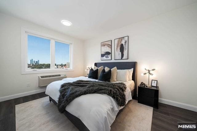 bedroom featuring baseboards, a wall mounted AC, and wood finished floors