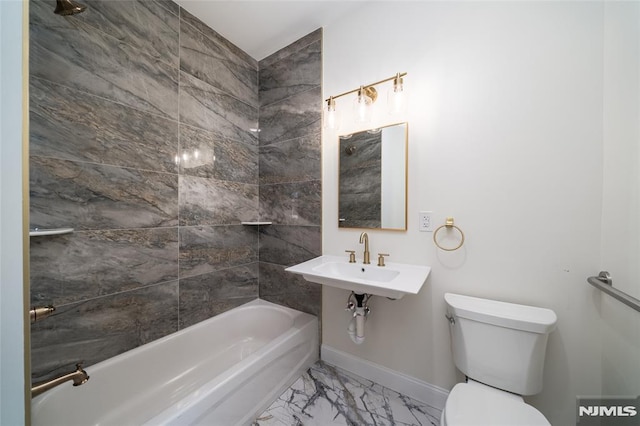 bathroom with marble finish floor, bathing tub / shower combination, toilet, baseboards, and a sink