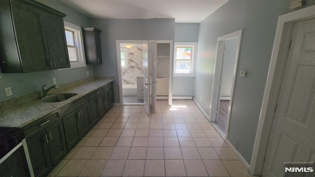 kitchen with light tile patterned flooring, light stone counters, a sink, a baseboard radiator, and a baseboard heating unit