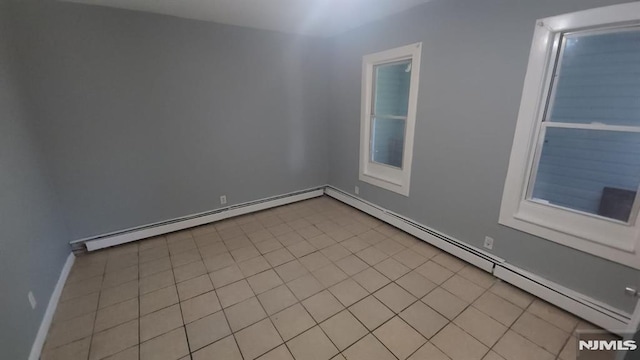 spare room featuring light tile patterned floors, baseboards, and baseboard heating