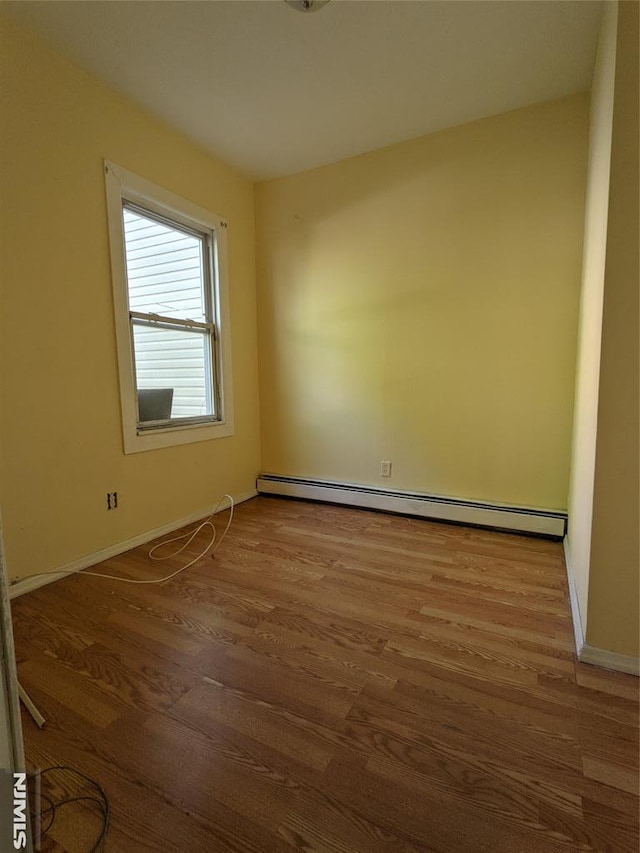 unfurnished room featuring baseboards, a baseboard radiator, and wood finished floors