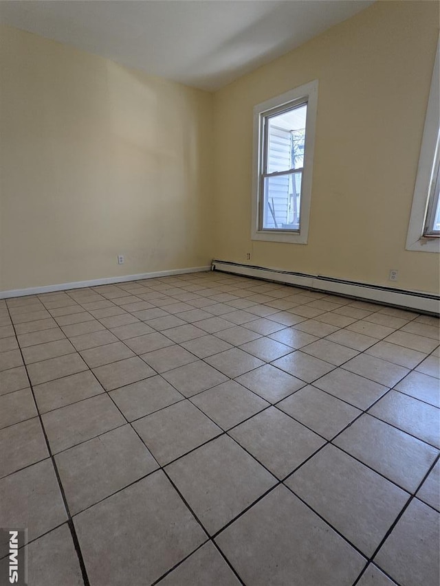 empty room with baseboards, a baseboard heating unit, and light tile patterned floors